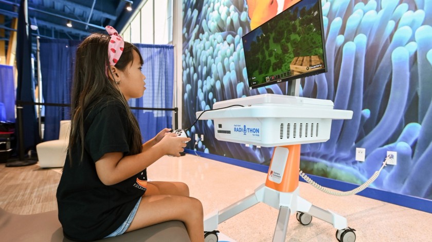 A young patient sitting and playing Minecraft on a GO Kart at a hospital.